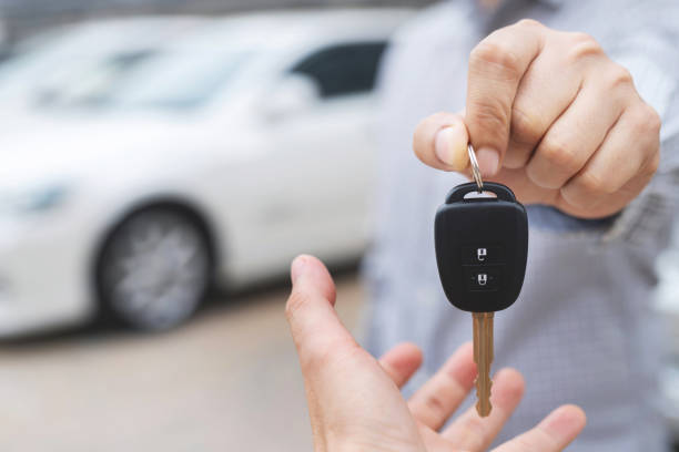 Sales man hold the key deliver cars to customers in the showroom with low interest promotions. Sales man hold the key deliver cars to customers in the showroom with low interest promotions. car key photos stock pictures, royalty-free photos & images