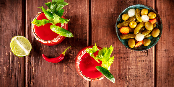 Bloody Mary cocktail panorama, tomato juice, lime, and celery, shot from the top on a rustic background, a flat lay