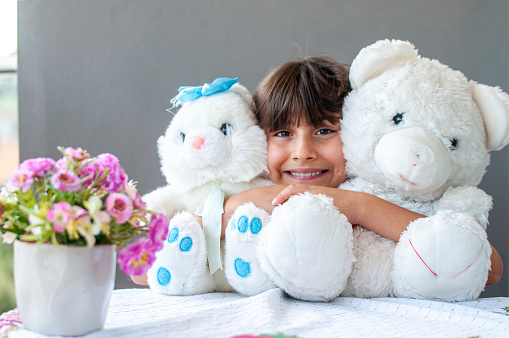 Little cute girl happiness at balcony with her teddy bear and plush rabbit