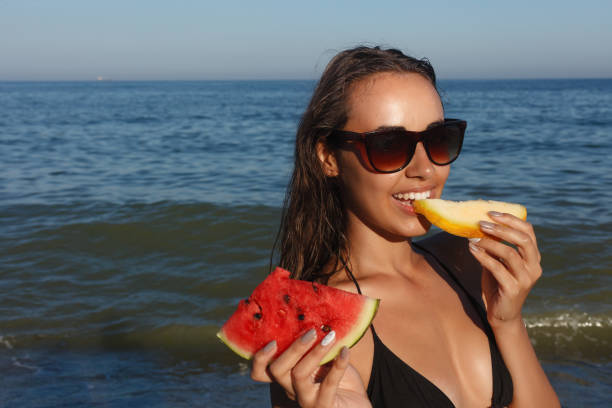 istock Summer vacation - young girl eating fresh watermelon on sandy beach 1221597655