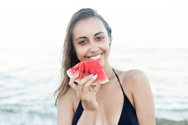 istock Summer vacation - young girl eating fresh watermelon on sandy beach 1221598029