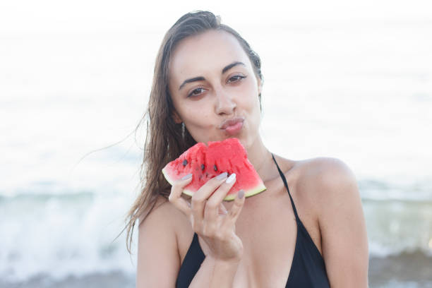 istock Summer vacation - young girl eating fresh watermelon on sandy beach 1221598067