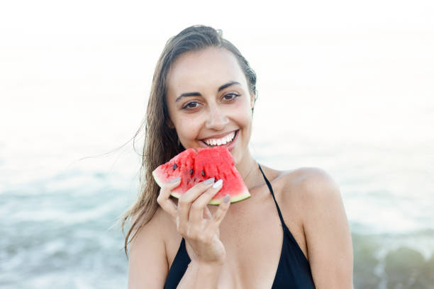 istock Summer vacation - young girl eating fresh watermelon on sandy beach 1221598068
