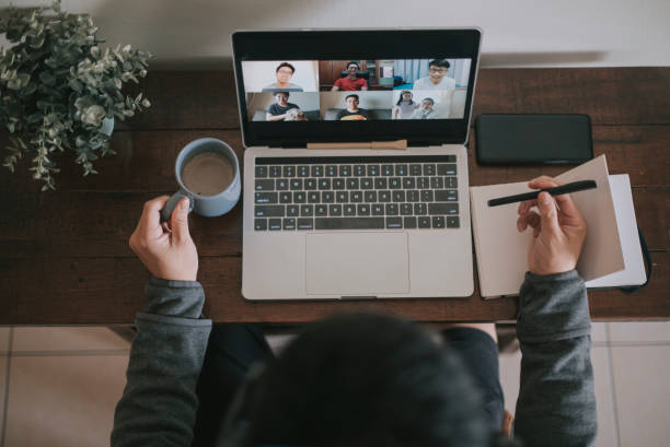 An asian chinese male working at home using laptop video conference call meeting with headset An asian chinese male working at home using laptop video conference call meeting work from home image stock pictures, royalty-free photos & images