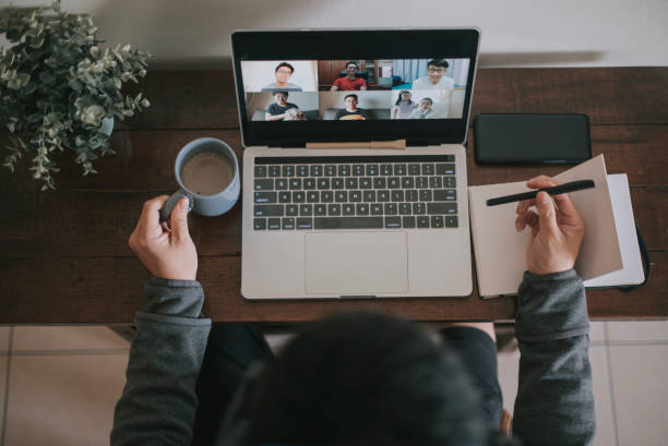 an asian chinese male working at home using laptop video conference call meeting with headset - computer keyboard fotos imagens e fotografias de stock