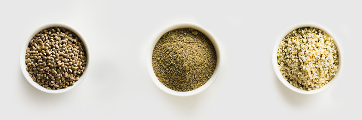 Organic dried hemp seeds, flour, kernels in white bowls isolated on white. View from above. Healthy ingredient.