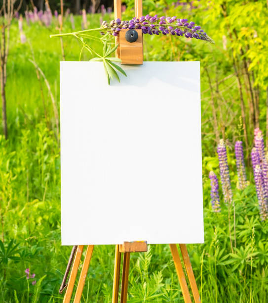 istock Wooden easel with white paper on nature background 1221600135