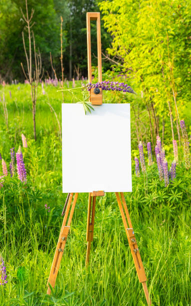 istock Wooden easel with white paper on nature background 1221600149