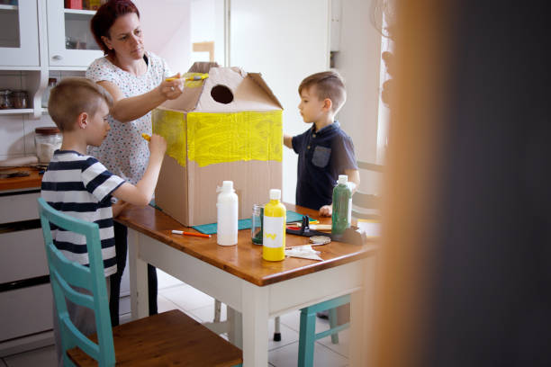 mamá y los niños haciendo un traje de dinosaurio de cartón - craft project fotografías e imágenes de stock