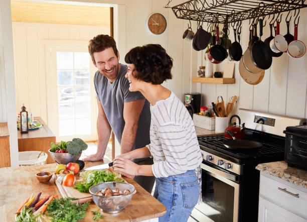 istock Young couple laughing while preparing a healthy meal in their kitchen 1221600329