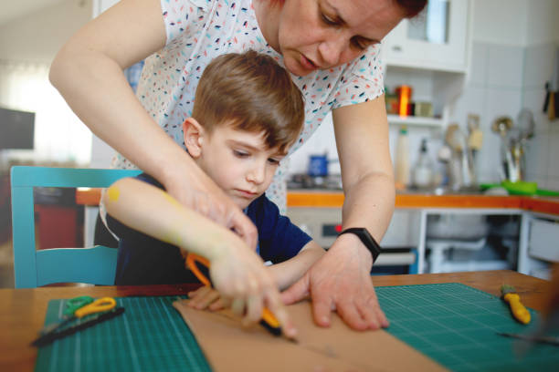 istock Mother helping son to cut cardboard, quarantine project 1221600673