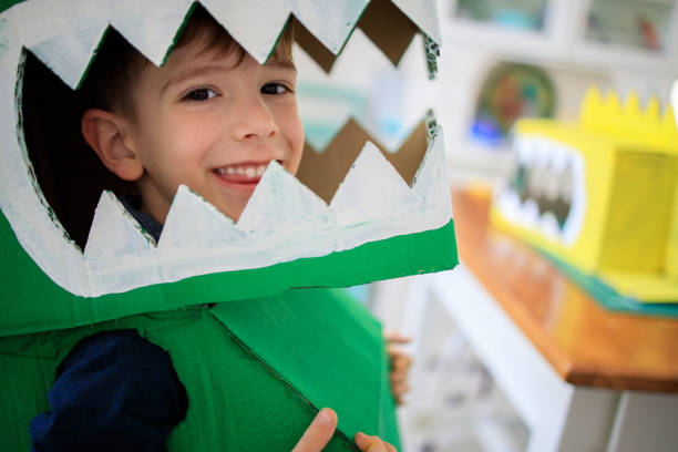 istock Smiling boy wearing a cardboard dinosaur costume 1221601521