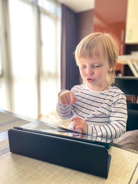 istock A fair-skinned little child sitting at a table in the kitchen, self-learning using a tablet.Defocus light background. 1221601697