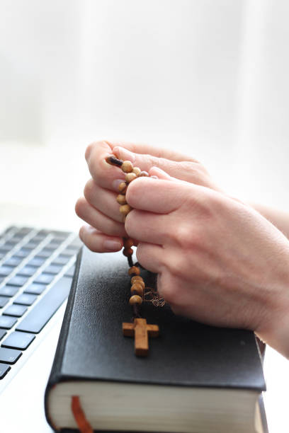 istock Internet Mass. A woman prays at the rosary. 1221601863