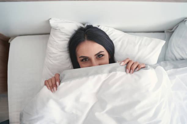 istock Cheerful brunette girl lying under the blanket 1221605697