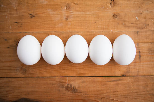 istock White eggs in a row on wooden background 1221606685
