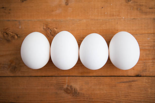 istock Four white eggs on the wooden background 1221606692