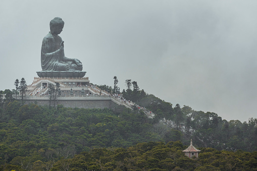 The Tian Tan Buddha on the mountain in Ngong Ping, Hong Kong in a cloudy day. Tian Tan Buddha, also known as the Big Buddha, is a large bronze statue, located at Ngong Ping, Lantau Island, in Hong Kong.