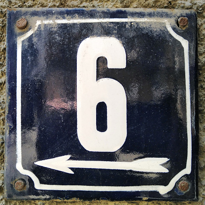 Weathered grunge square metal enameled plate of number of street address with number 6 closeup