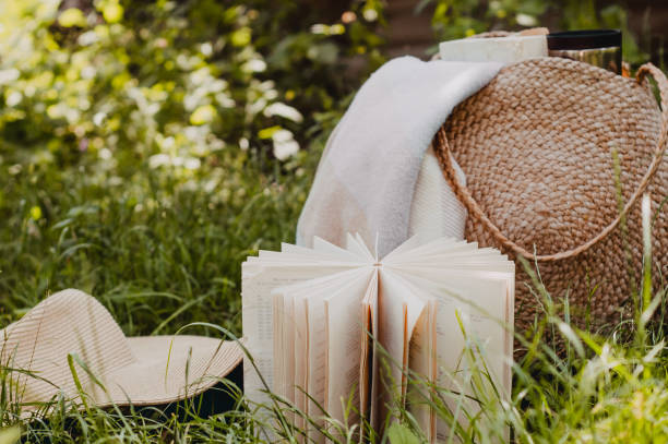 istock Straw bag, book, hat and thermo cup on a sunny summer day 1221608629