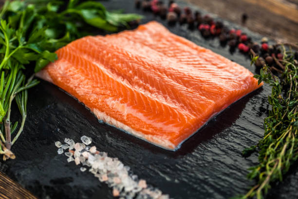 istock one big salmon steak with greenery and pepper and salt grains on the black board 1221610003