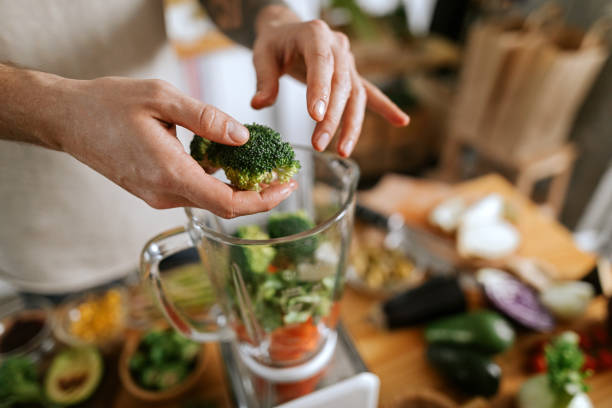 uomo che prepara succo di verdura - blender foto e immagini stock