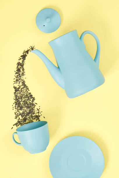 istock minimalism concept with light pastel colored blue teapot pouring tea and cup on yellow background.  Flat lay. Tea time concept. Empty space 1221610396
