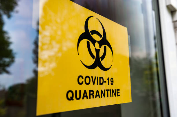 istock COVID-19 QUARANTINE  sign in window. 1221610633