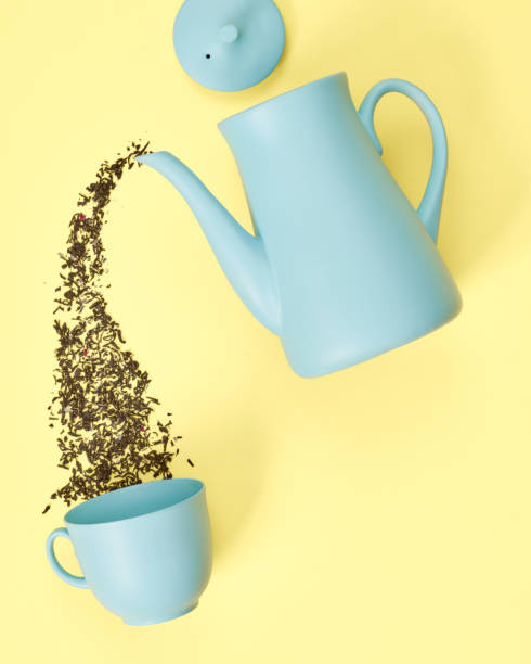 istock minimalism concept with light pastel colored blue teapot pouring tea and cup on yellow background.  Flat lay. Tea time concept. Empty space 1221611071