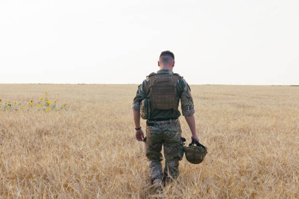 istock Soldier man standing against a field 1221612533