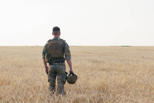 istock Soldier man standing against a field 1221613187