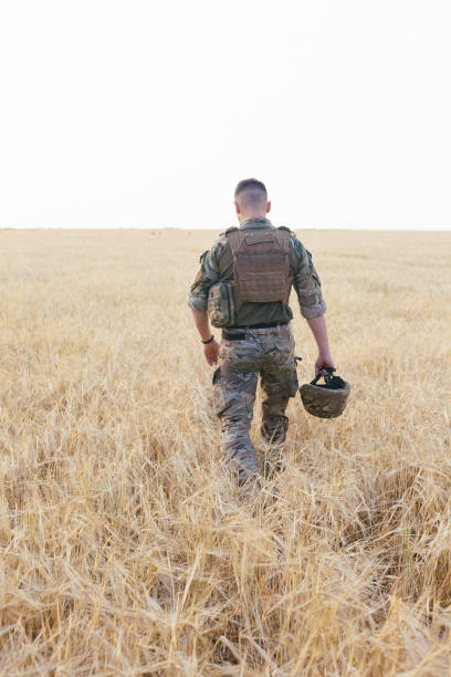 istock Soldier man standing against a field 1221613229