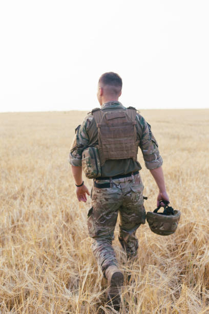 istock Soldier man standing against a field 1221613417