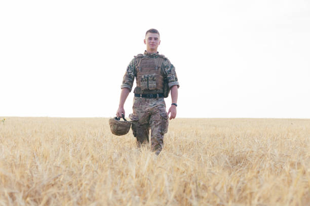 istock Soldier man standing against a field 1221613525