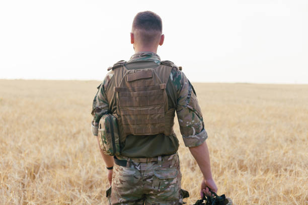 istock Soldier man standing against a field 1221614579