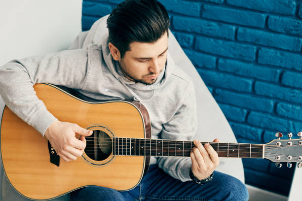 istock close-up of handsome man playing on guitar with blue wall on background 1221615348