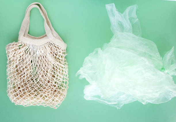 istock String reusable bag and a pile of plastic bags on green background, zero vaste concept. Top view 1221618214