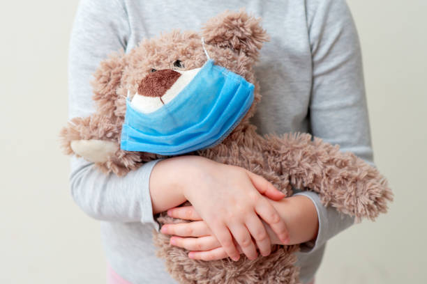istock Toy bear with protective mask in child hands. 1221619526