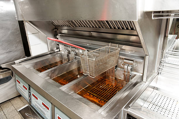An empty deep fryer with oil in bins and baskets on top