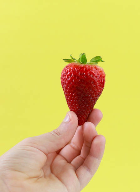 istock A hand holding a strawberry 1221624383