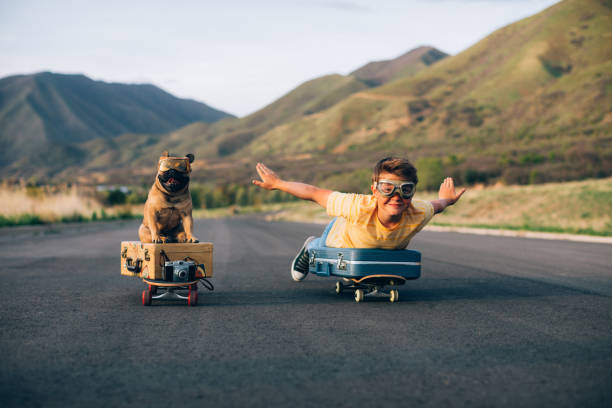 A young boy and his French Bulldog are ready to travel the world. They have put their suitcases on skateboards and are wearing flight goggles, ready to fly to new places and heights. Image taken in Utah, USA.