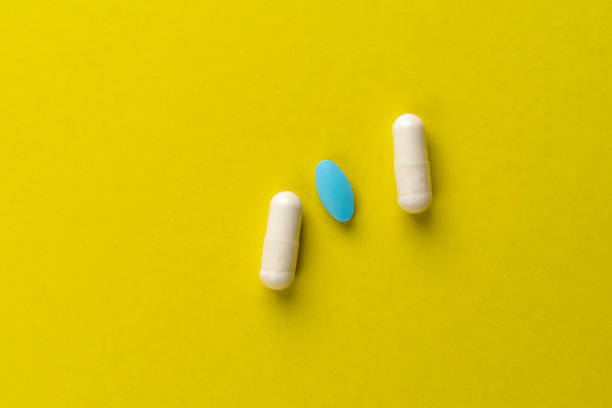 istock 2 white pills and 1 blue tablet on a yellow background. 1221625871