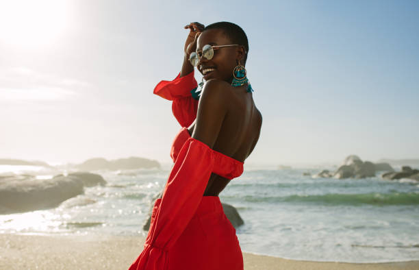 Beautiful african woman in red dress enjoying on the beach Beautiful african woman in red dress enjoying on the beach. Smiling female in beautiful dress walking along the shore. red dress photos stock pictures, royalty-free photos & images