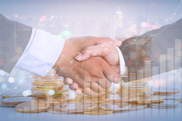 istock Successful cooperative, teamwork, and joint venture concept; double exposure of handshake and coins stack, with growing trend graph. 1221626646