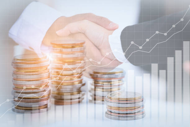 istock Successful cooperative, teamwork, and joint venture concept; double exposure of handshake and coins stack, with growing trend graph. 1221626666