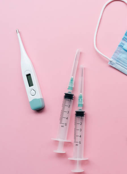 istock Mask, electronic thermometer, empty syringe with light pink background.Covid 19. 1221626844