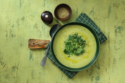 Vegetarian Creamy Green Peas Soup. Flat lay top-down composition on green background