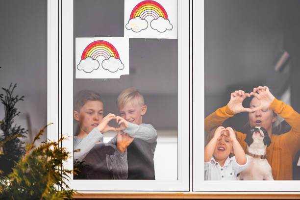 Quarantined family, mother with her three sons photographed through a window, Canada
