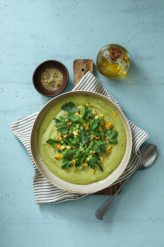 Spinach and Green Pea Soup with Grilled Corn. Flat lay top-down composition on blue background.
