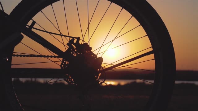 Close up of bike wheels and female feet shoes cycling outside city in spring evening taking care of environment at sunset in slow motion